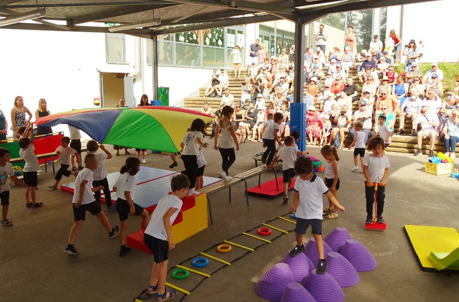 Les enfants de l'école lors de la kermesse, sous le préau, devant les familles